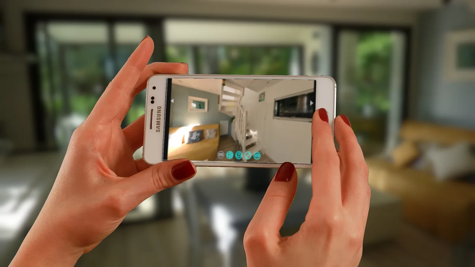 Deux mains tiennent un smartphone qui affiche la visite virtuelle 360° d'un salon de gîte