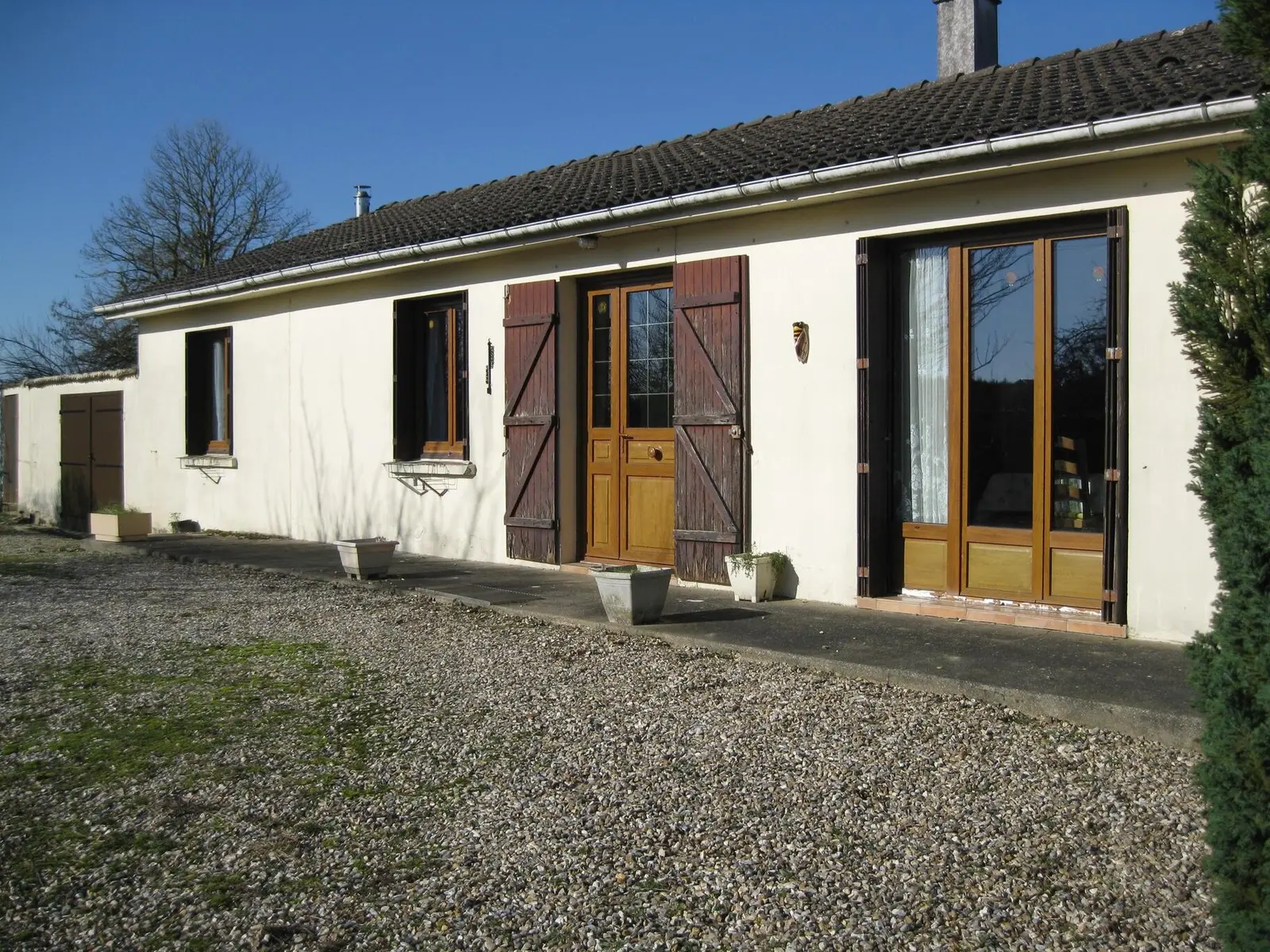 Pavillon de plain-pied à Beaussault, volets bruns et cour gravillonnée, sous un ciel bleu